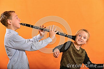 The boy plays the clarinet in the girlâ€™s ear, the outraged girl waves her arms Stock Photo